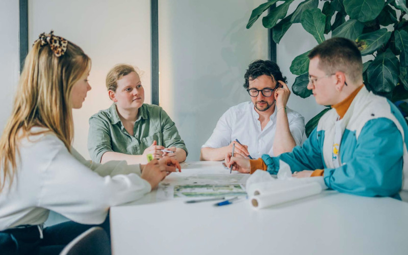 Vier Menschen sitzen bei einem Meeting an einem Büro-Tisch